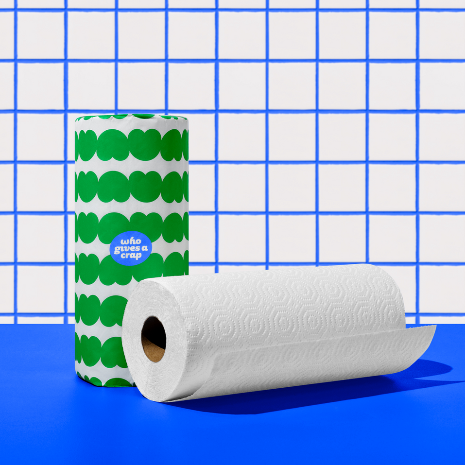 Two rolls of Who Gives a Crap paper towel against blue and white background