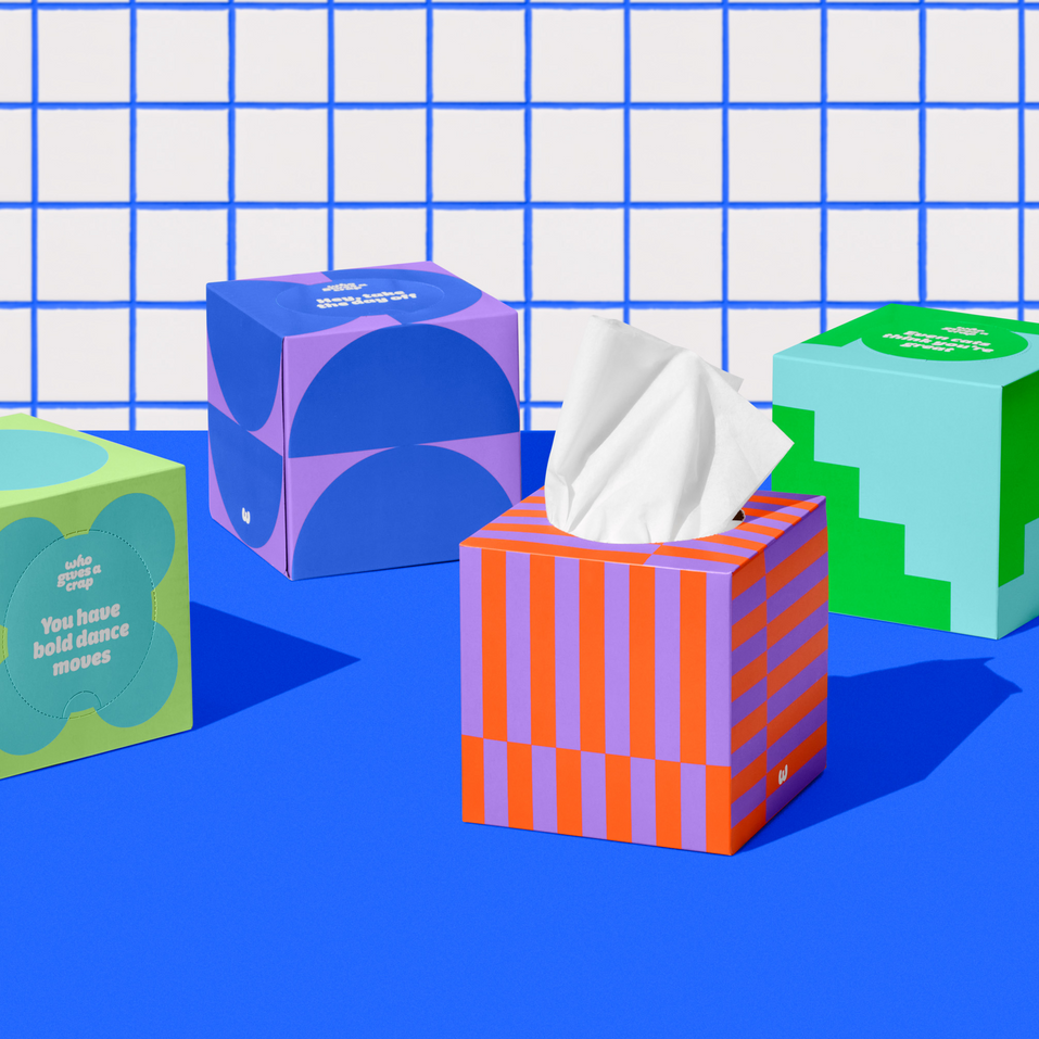 Four boxes of of Who Gives a Crap recycled tissues against blue and white bathroom wall