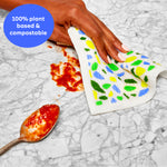 Hand using a plant based and compostable Swedish dish cloth to clean up a red tomato sauce mess on a countertop