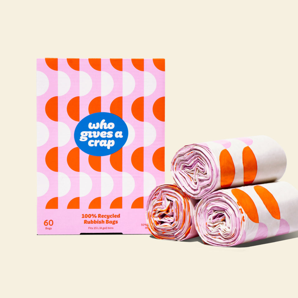 Three rolls of 100% recycled trash bags next to a pink and orange box that contains 60 bags designed to fit 15L bins.