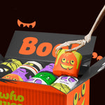 Open Spooky Edition box of toilet paper with skeleton hand lifting pumpkin-themed roll, surrounded by colourful monster wrappers
