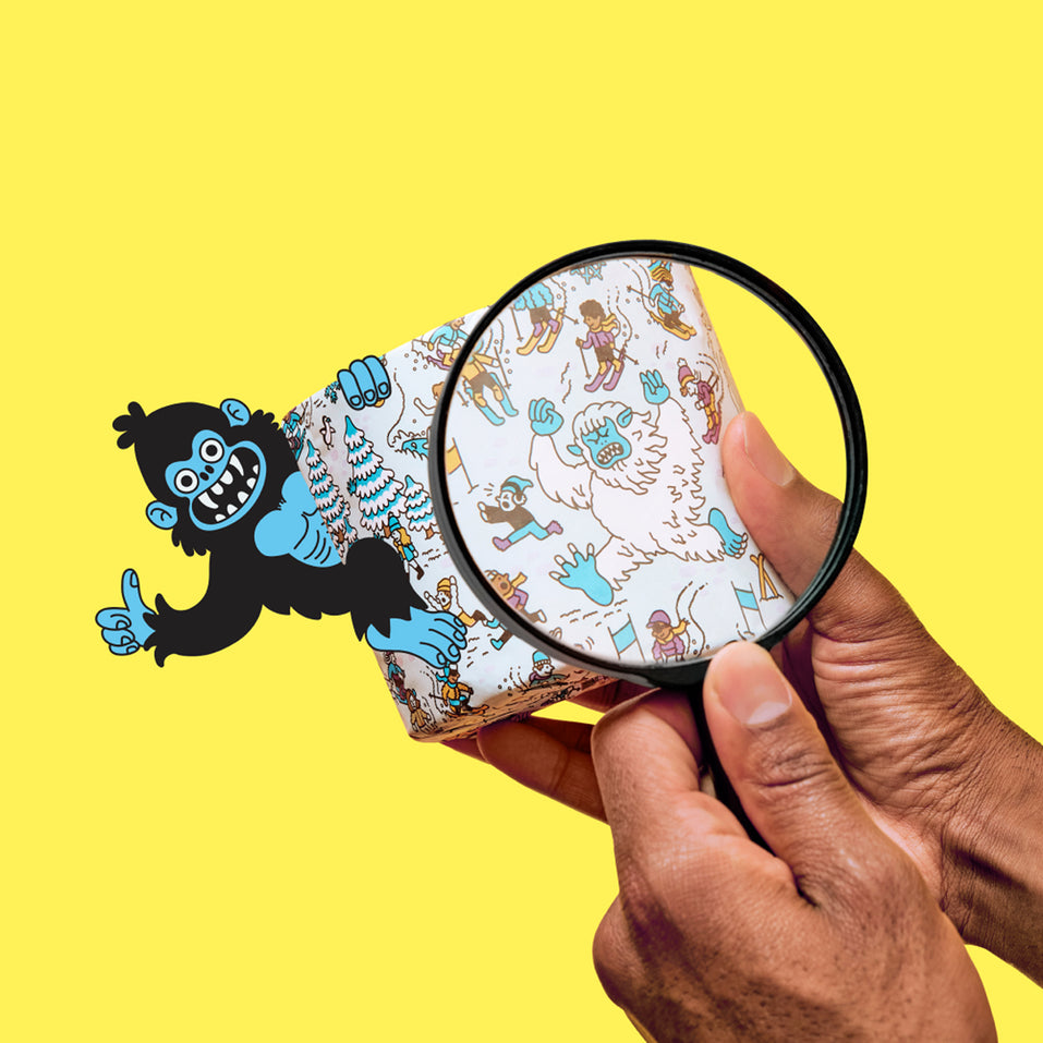 Person holding a magnifying glass over a patterned toilet paper with a cartoon character on a yellow background
