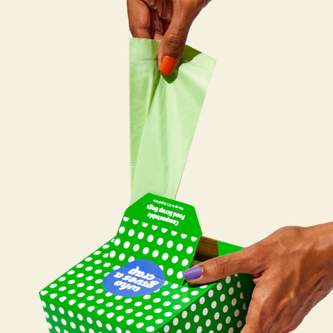 Hand pulling a compostable food scrap bag from the box, showcasing easy dispensing and quick access.