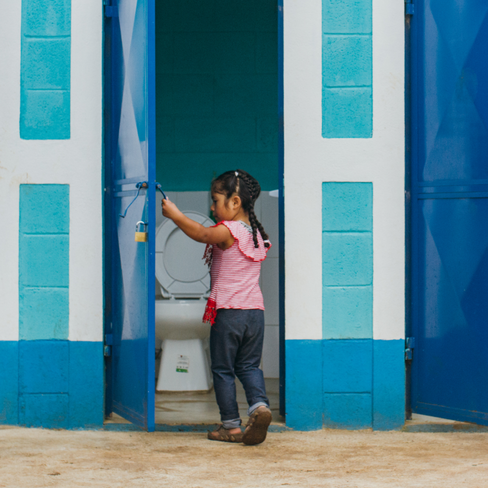 Young child opening door to bathroom cubicle.