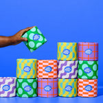 Recycled Toilet Paper in colorful packaging with a hand lifting up one roll of toilet paper