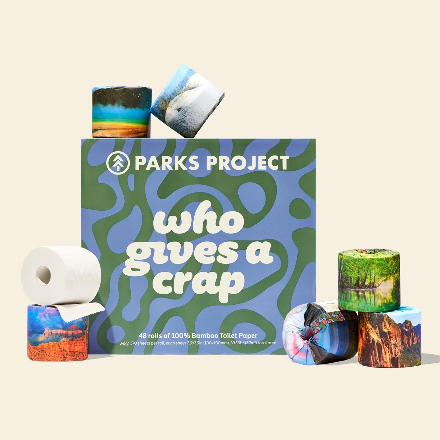 A blue and green patterned box with the words ‘Who Gives A Crap’, surrounded by stacks of eco-friendly toilet paper rolls wrapped with landscape nature photography.