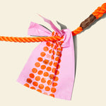 A dog poo bag tied to an orange dog leash, showing how the bag will look in use.