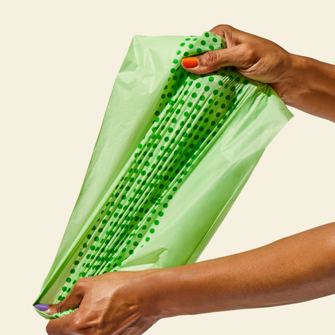 Hand pulling a compostable food scrap bag, highlighting the strength and durability of the bag.