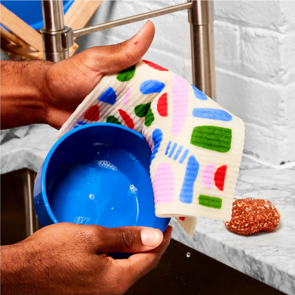 Person cleaning dirty dishes in sink using Who Gives a Crap dream cloth