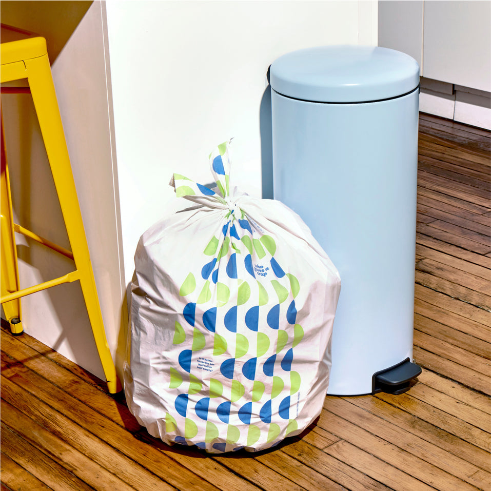 Who Gives a Crap large recycled trash bag sits full next to kitchen bin.